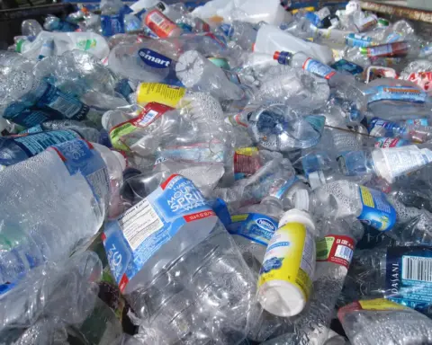 Stacks of discarded plastic and glass bottles at a recycling collection point, symbolizing the chemical contamination cycling through water systems.