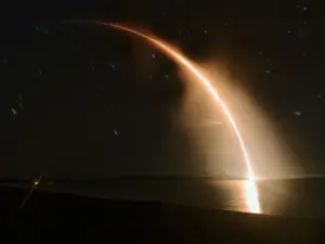 A Rocket Lab Electron rocket ascending over the ocean in a long-exposure night launch.