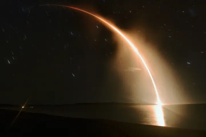 A Rocket Lab Electron rocket ascending over the ocean in a long-exposure night launch.