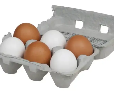Close-up of brown and white chicken eggs in a cardboard carton