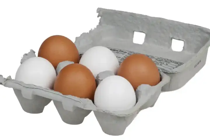 Close-up of brown and white chicken eggs in a cardboard carton