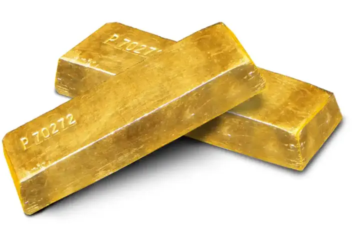 Stacked gold bars and gold coins arranged on a white surface