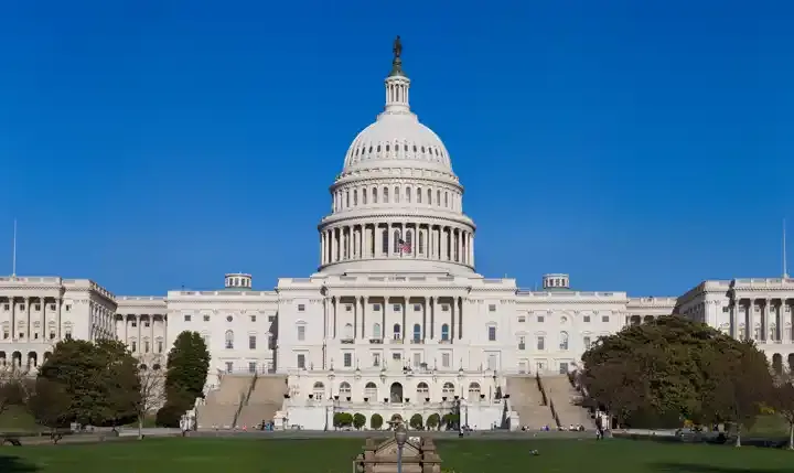 Exterior view of the United States Capitol building in Washington, D.C., showing the western front with its central dome and legislative wings.