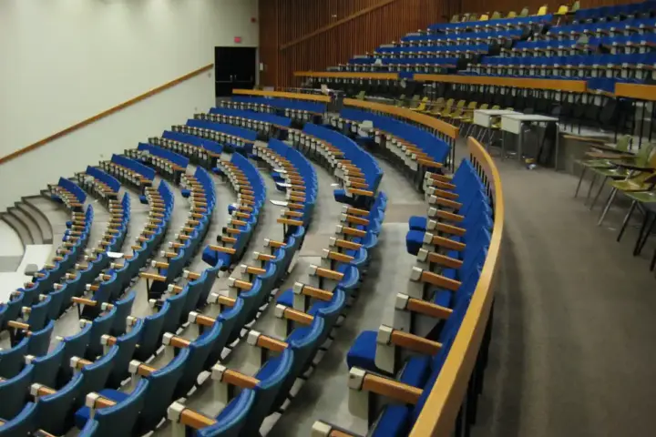Empty university lecture hall with tiered wooden seats and a lectern