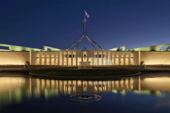 Parliament House Canberra exterior at dusk with Australian flag flying