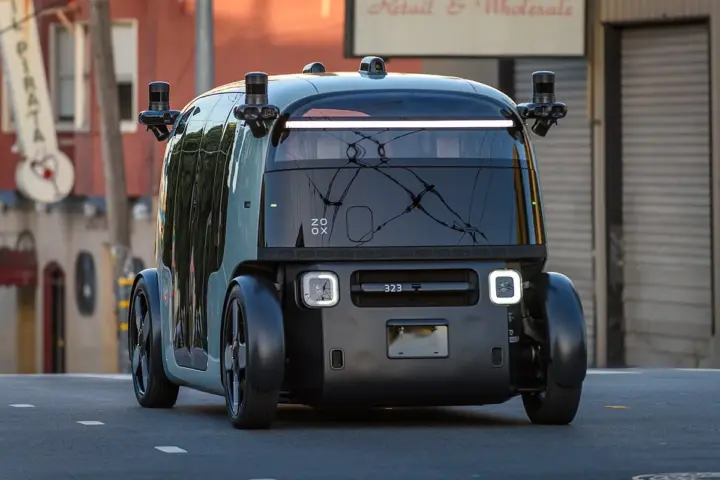 Zoox autonomous robotaxi pod with roof lidar crossing a San Francisco street