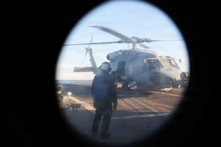 U.S. Navy sailor watches an MH-60R Sea Hawk during operations aboard USS Roosevelt in the Strait of Hormuz.