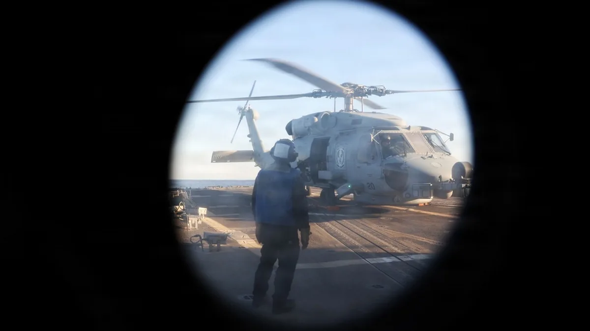 U.S. Navy sailor watches an MH-60R Sea Hawk during operations aboard USS Roosevelt in the Strait of Hormuz.