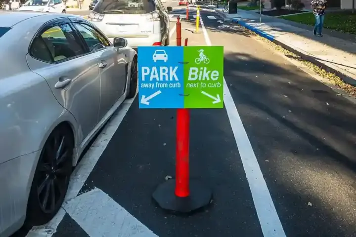 Curbside green-painted bicycle lane and pedestrian crosswalk along an urban street corridor
