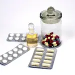 Close-up photograph of assorted pharmaceutical blister strips and medicinal tablets on a clean surface.