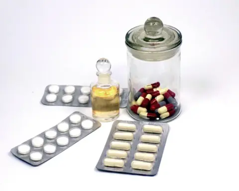 Close-up photograph of assorted pharmaceutical blister strips and medicinal tablets on a clean surface.