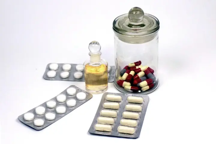 Close-up photograph of assorted pharmaceutical blister strips and medicinal tablets on a clean surface.