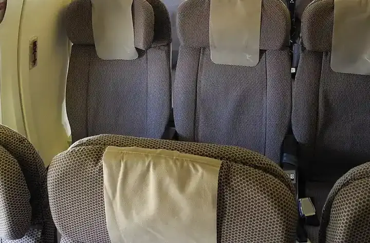 Rows of commercial airplane passenger seats inside a narrow aircraft cabin without visible airline branding