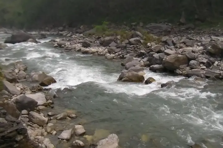 Steep mountainous river gorge with water flowing through boulders in the high Himalayas of Nepal.