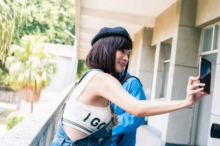 A person holding a smartphone outdoors while using the camera app to frame a portrait photograph.