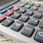 Money and a calculator used for a personal finance comparison.