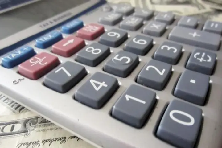 Money and a calculator used for a personal finance comparison.