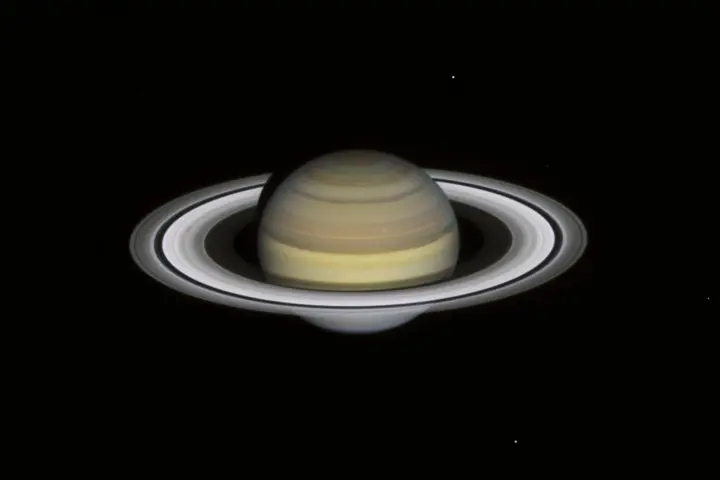Full planetary disk of Saturn showing atmospheric bands and tilted ring system against the black background of space.