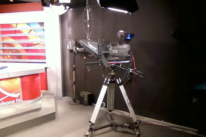 Television news studio camera positioned beside professional lighting and broadcast production equipment