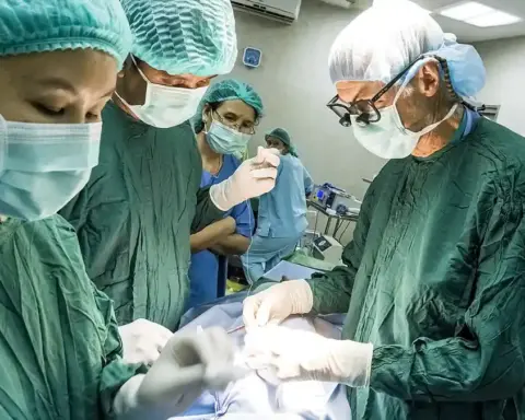 Specialized surgical transplant team performing complex surgery in an operating theater under overhead lights.