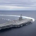 Aerial view of the Nimitz-class aircraft carrier USS Abraham Lincoln (CVN-72) navigating open ocean waters.