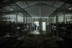 Interior view of the Alligator Alcatraz detention facility showing enclosed areas and rows of bunks.