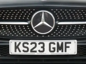 Close-up of a front white reflective UK registration plate mounted cleanly on the grille bumper of a modern road car.