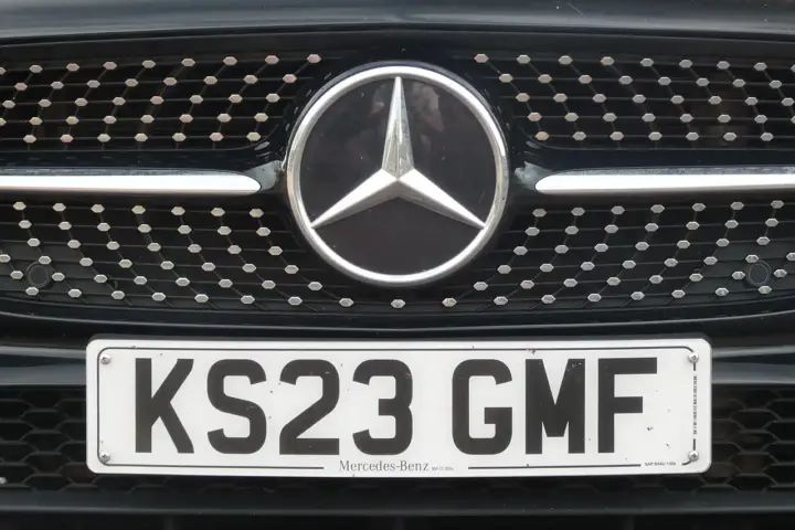 Close-up of a front white reflective UK registration plate mounted cleanly on the grille bumper of a modern road car.
