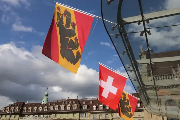 Swiss and Bern flags displayed at Bahnhofplatz in Bern, Switzerland.