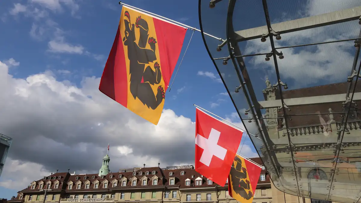 Swiss and Bern flags displayed at Bahnhofplatz in Bern, Switzerland.