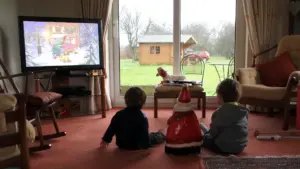 Children seated in front of a television in a family living room.