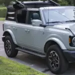 Photograph of a blue four-door Ford Bronco Outer Banks SUV parked outdoors on asphalt.