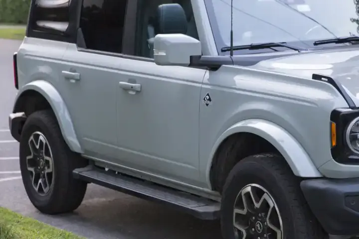 Photograph of a blue four-door Ford Bronco Outer Banks SUV parked outdoors on asphalt.