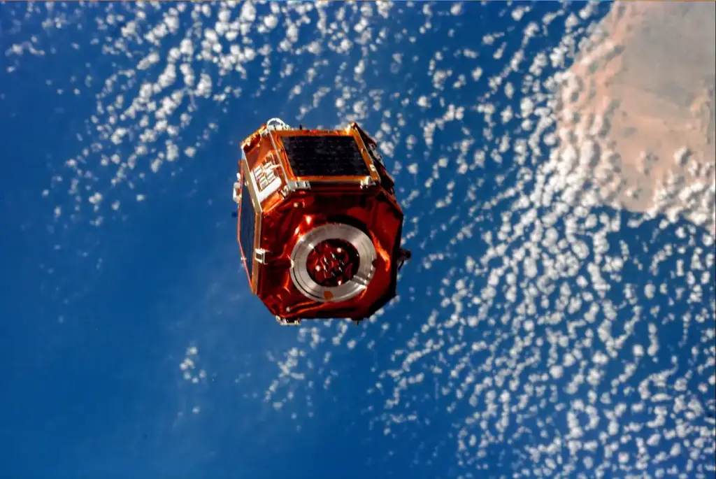 Photograph taken from space showing an orbital satellite deployed against the blue curve of Earth.