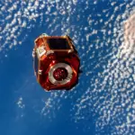 Photograph taken from space showing an orbital satellite deployed against the blue curve of Earth.