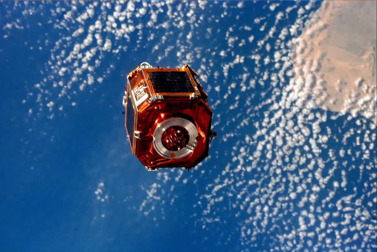 Photograph taken from space showing an orbital satellite deployed against the blue curve of Earth.