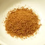 Photograph of unhulled whole sesame seeds placed in a small preparation bowl.
