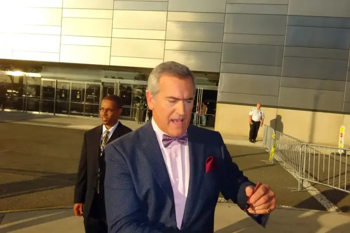 Close-up color photograph of actor Bruce Campbell speaking candidly into a microphone during a panel discussion.