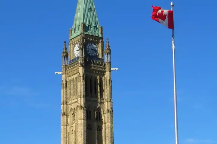 Gothic revival Parliament Hill tower and Canadian flag in Ottawa.