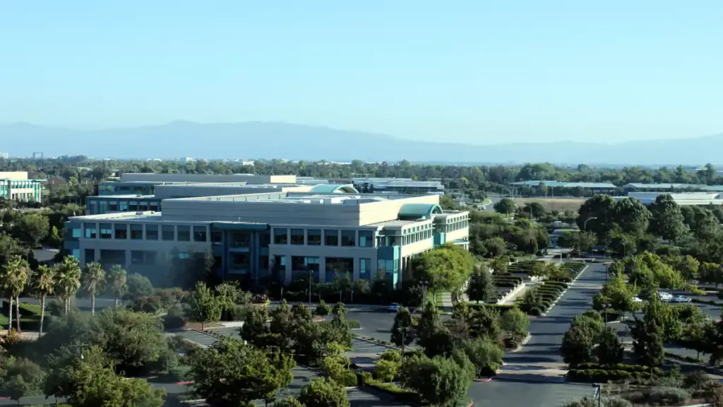 Wide-angle photograph of the Cisco Systems corporate headquarters campus and glass exterior office complex in San Jose, California.