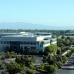 Wide-angle photograph of the Cisco Systems corporate headquarters campus and glass exterior office complex in San Jose, California.