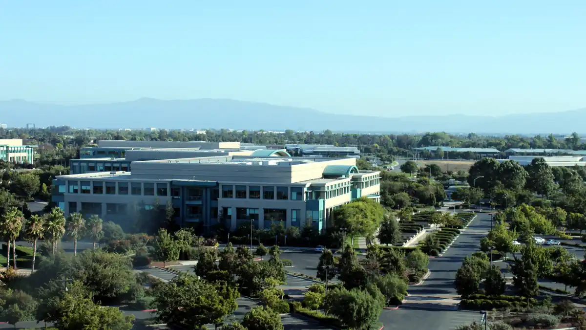 Wide-angle photograph of the Cisco Systems corporate headquarters campus and glass exterior office complex in San Jose, California.