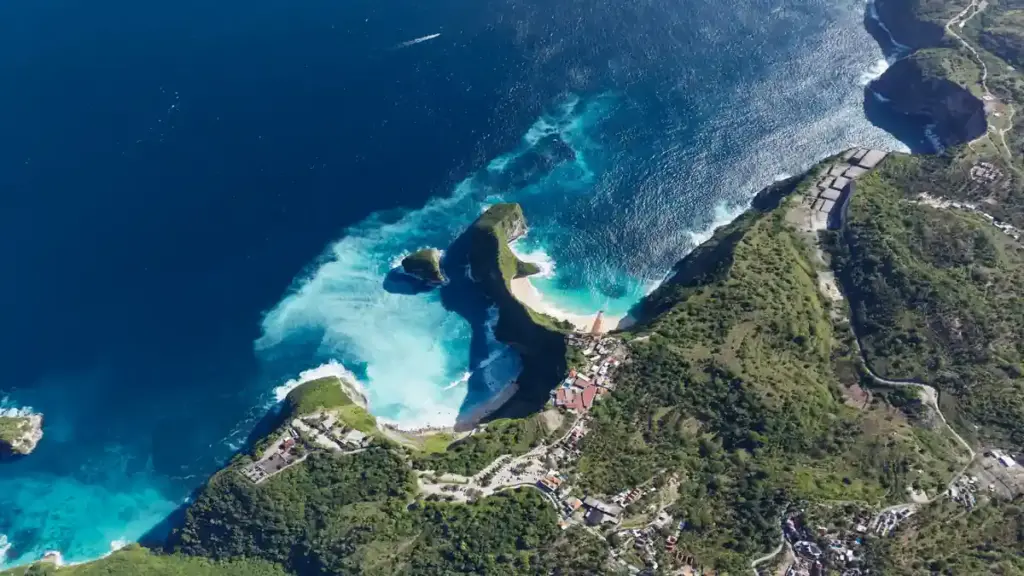 Aerial view of the steep coastal limestone cliffs and turquoise cove at Kelingking Beach on Nusa Penida