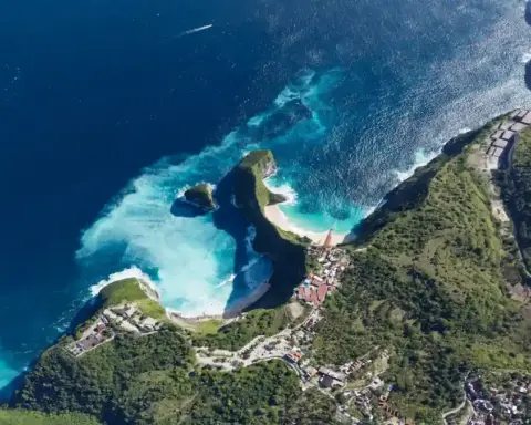 Aerial view of the steep coastal limestone cliffs and turquoise cove at Kelingking Beach on Nusa Penida