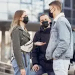 People wearing face masks in an urban setting, illustrating COVID-19 respiratory-virus coverage in Australia