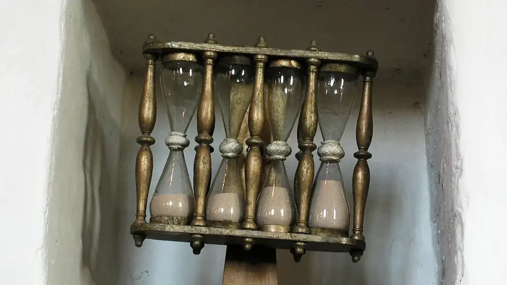 A glass hourglass in a wooden frame used for traditional timekeeping.