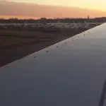 A commercial airplane wing seen during flight near an airport.