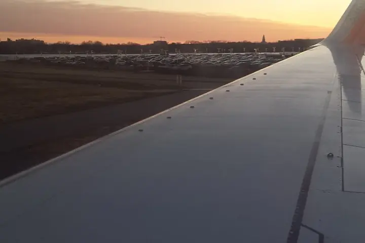 A commercial airplane wing seen during flight near an airport.