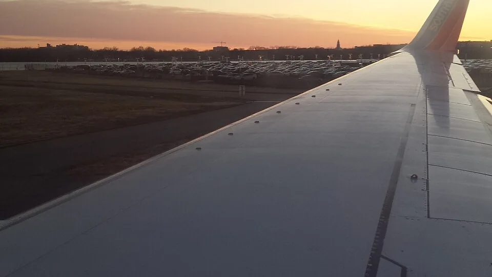 A commercial airplane wing seen during flight near an airport.