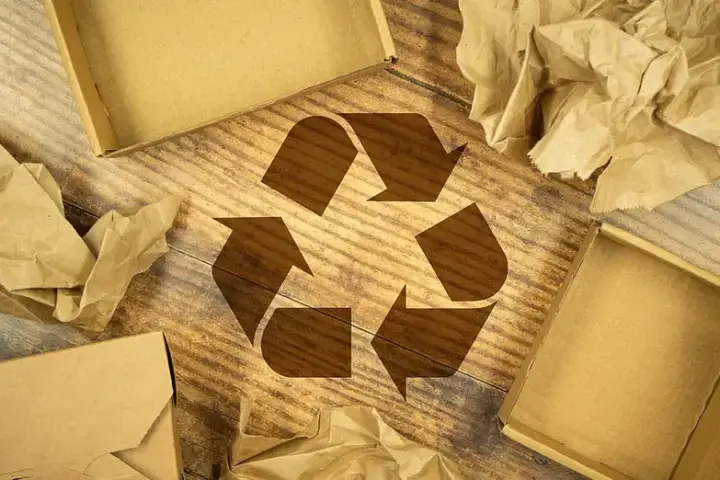 Recycling symbol surrounded by cardboard boxes and paper packaging